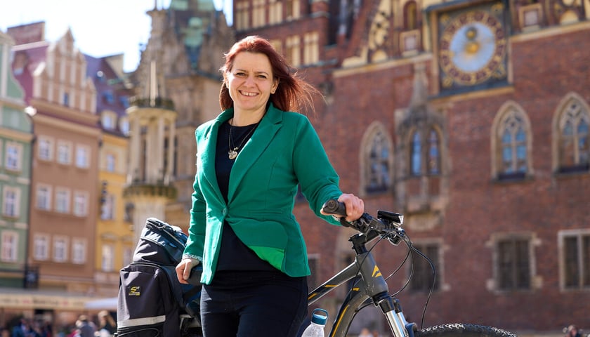 Powiększ obraz: <p>Radna miejska Agnieszka Dusza z rowerem na tle wrocławskiego Ratusza. Zdjęcie archiwalne z 2024 roku.</p>
