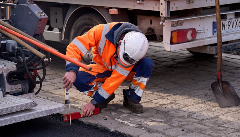 Powiększ obraz: Układanie masy bitumicznej na ulicy Powstańców Śląskich między Orlą a Krzycką