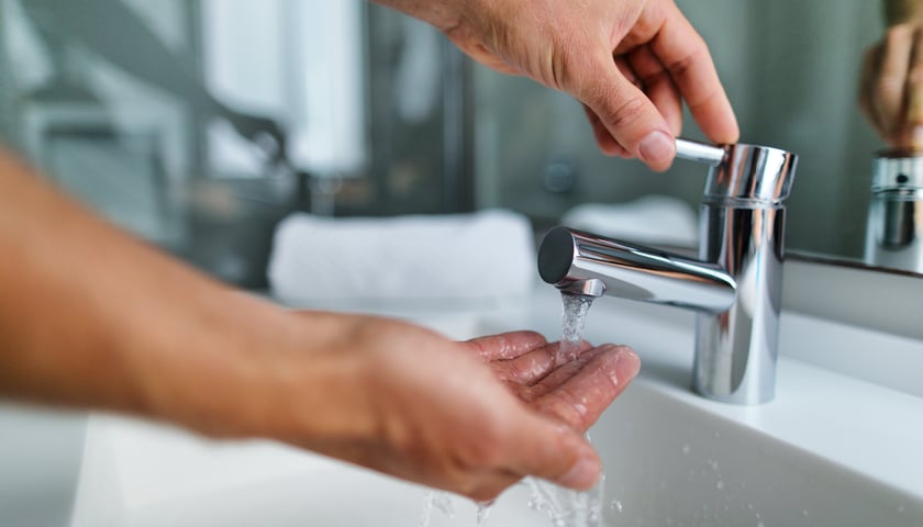 Powiększ obraz: Ręka w strumieniu wody pod kranem