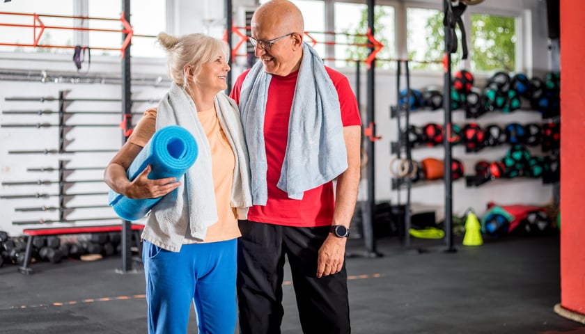 Powiększ obraz: Senior i seniorka w strojach do fitnessu na sali gimnastycznej