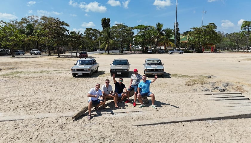 Powiększ obraz: Trzy retro pojazdy i grupa mężczyzn przed nimi - zdjęcie z wyprawy „Z Ziemi Tajskiej do Polski”