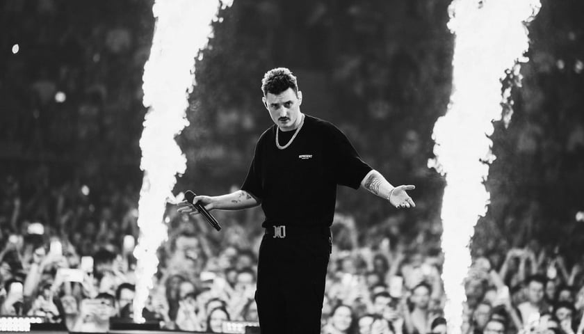 Dawid Podsiadło w ciemnym stroju i z mikrofonem podczas koncertu we Wrocławiu