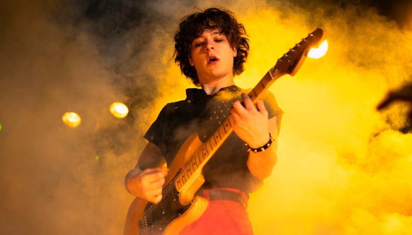 Aktor Mikołaj Bukrewicz w roli Jana Borysewicza występuje na scenie grając na gitarze.