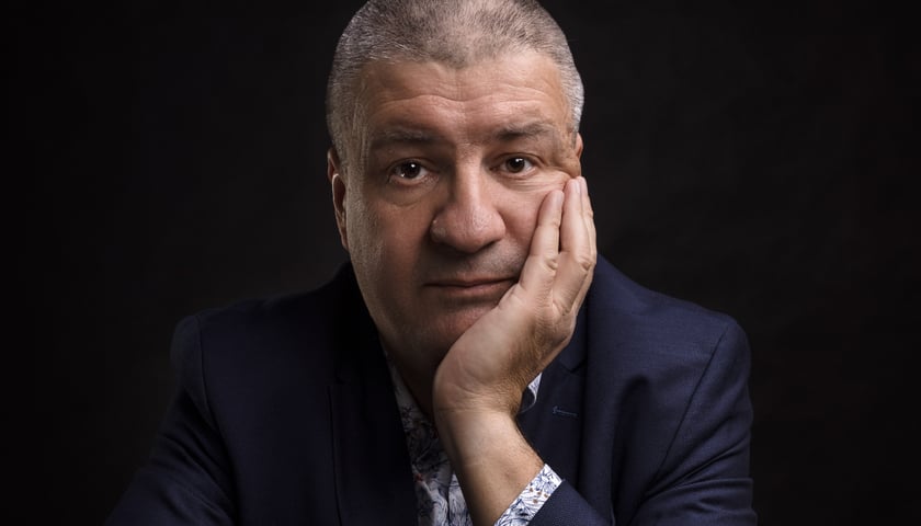 Pianista Kuba Stankiewicz pozuje podpierając twarz dłonią