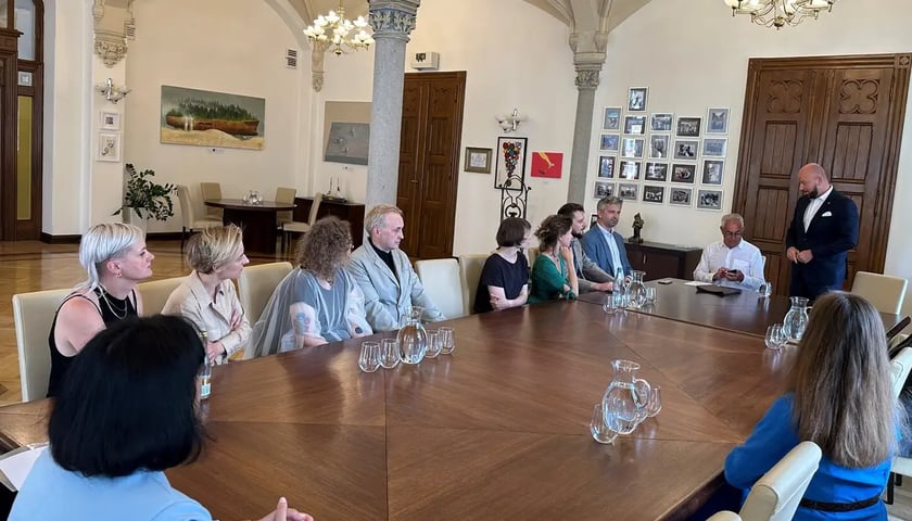 Prezydent Jacek Sutryk razem z laureatami stypendiów artystycznych pozuje do zdjęcia w swoim gabinecie 