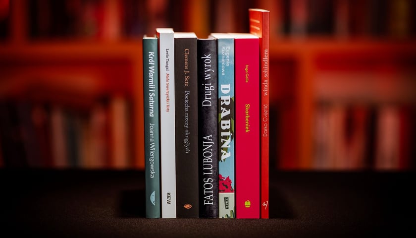Na zdjęciu grzbiety 7 książek, które znalazły się w finale Nagrody Angelus 2025