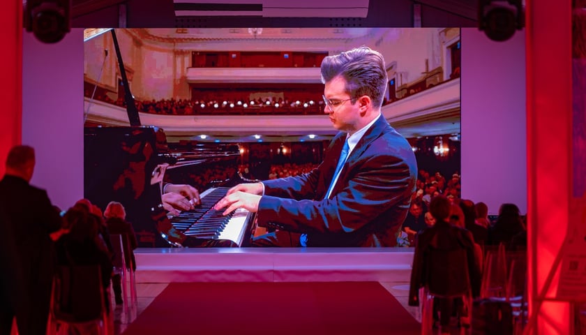 Na zdjęciu ekran, na którym widać grającego Piotra Alexewicza i publiczność w Strefie Melomana Konkursu Chopinowskiego na pl. Społecznym