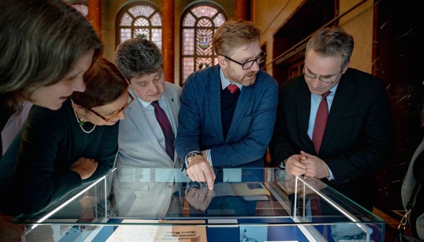 Grupa osób oglądająca eksponaty w gablocie. Wystawa  „Pojednanie dla Europy”  przygotowana przez Centrum Historii Zajezdnia w berlińskim ratuszu.