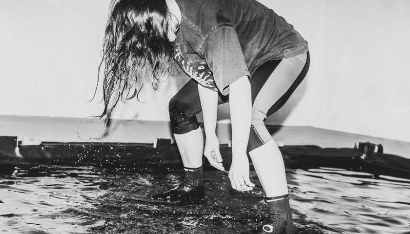 Pochylona aktorka stojąca w wodzie podczas próby w Pantomimie