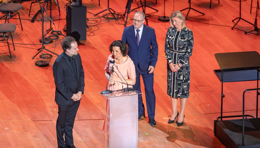 Gala Fryderyki 2026. Na scenie 4 osoby, przy mikrofonie Agnieszka Franków-Żelazny, wrocławska chórmistrzyni i dyrektor Opery Wrocławskiej ze statuetką Fryderyk za płytę „Universal Prayer”, z prawej strony wiceprezydent Wrocławia Renata Granowska, która wręczyła nagrodę.