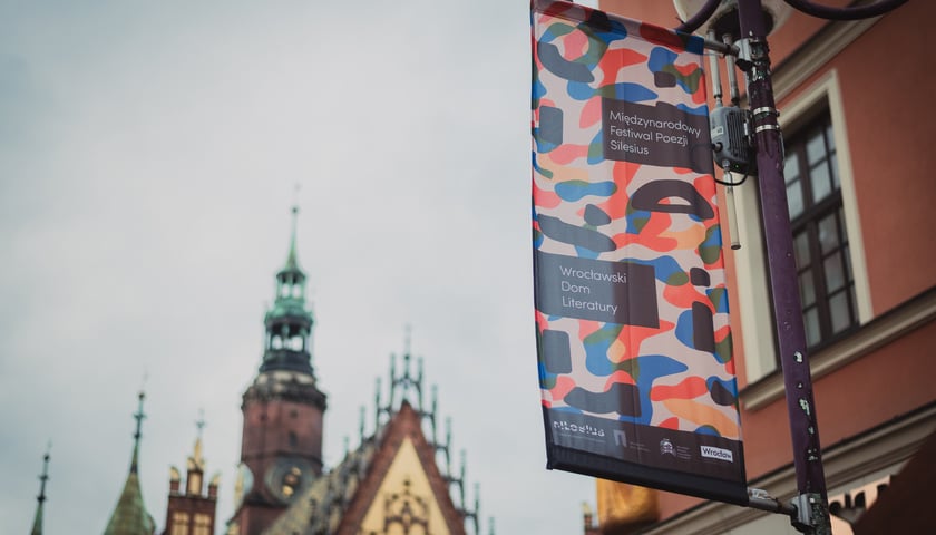 Na zdjęciu festiwalowa reklama w centrum Wrocławia, za nią widoczna wieża Ratusza