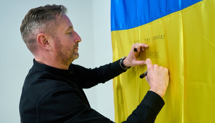 <p>Serhij Żadan podpisuje się na ukraińskiej fladze</p>