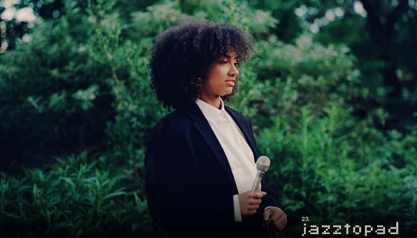 Wokalistka i kontrabasistka Esperanza Spalding na zdjęciu w czarno-białym stroju i z mikrofonem