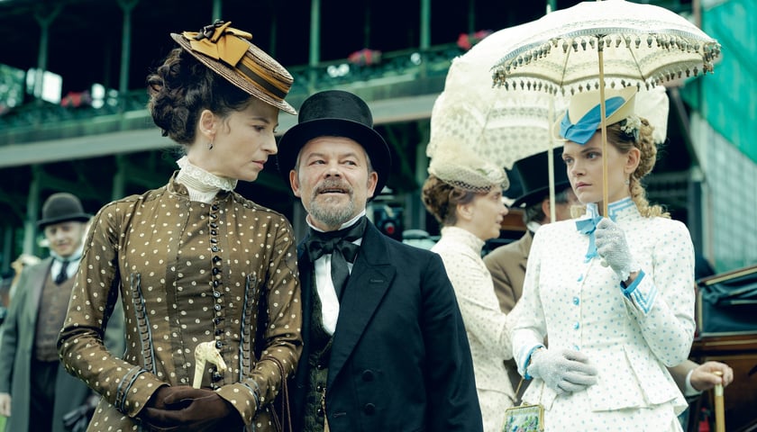 <p>Julia Wyszyńska (Florentyna), Jacek Braciak (Łęcki) i Sandra Drzymalska (Izabela). Scena z wyścig&oacute;w konnych. W tle Partynice. Zdjęcia z planu serialu "Lalka" Netflixa</p>