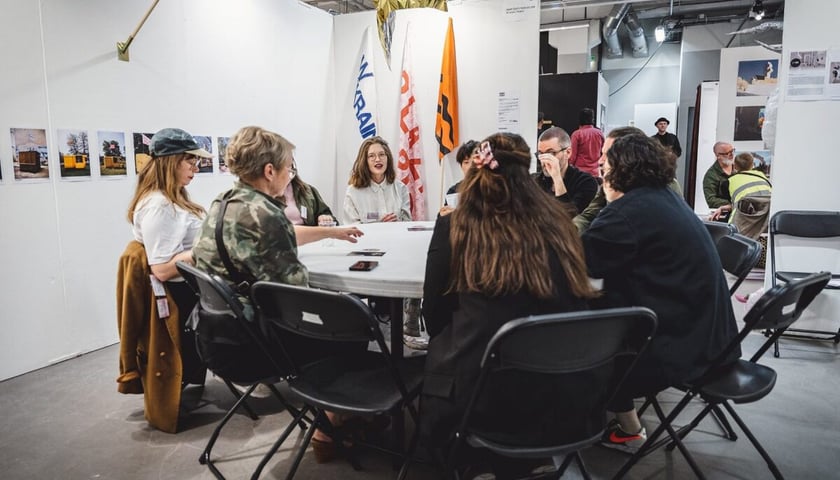 Na zdjęciu grupa osób siedzących przy okrągłym stole. Międzynarodowe targi sztuki niezależnej SUPERMARKET 2022.