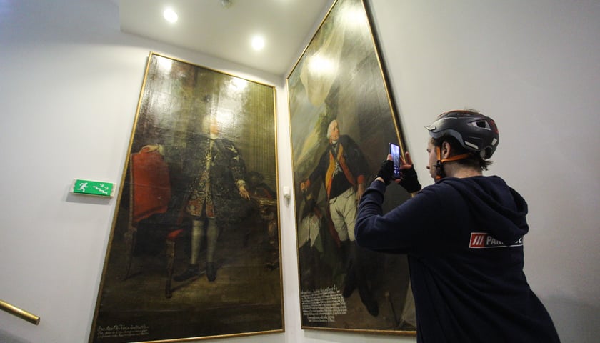 Powiększ obraz: Noc Muzeów w Pałacu Królewskim. Zwiedzający robi zdjęcie obrazom telefonem
