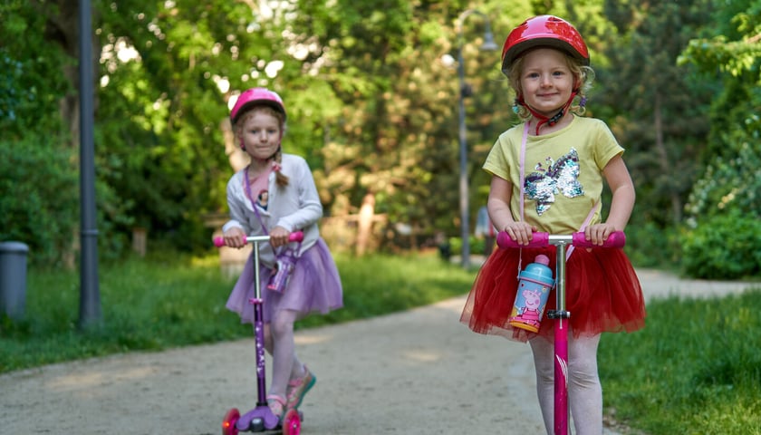 Powiększ obraz: <p>Dziewczynki na hulajnogach w Parku Staromiejskim. Gry miejskie są przeznaczone gł&oacute;wnie dla dzieci</p>