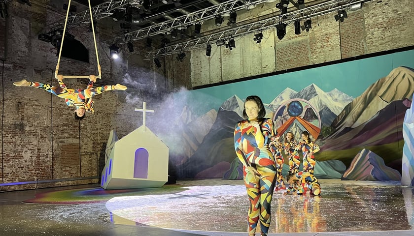 Aktorka pantomimy w kolorowym kostiumie na scenie, w tle: krajobraz górski (element scenografii)