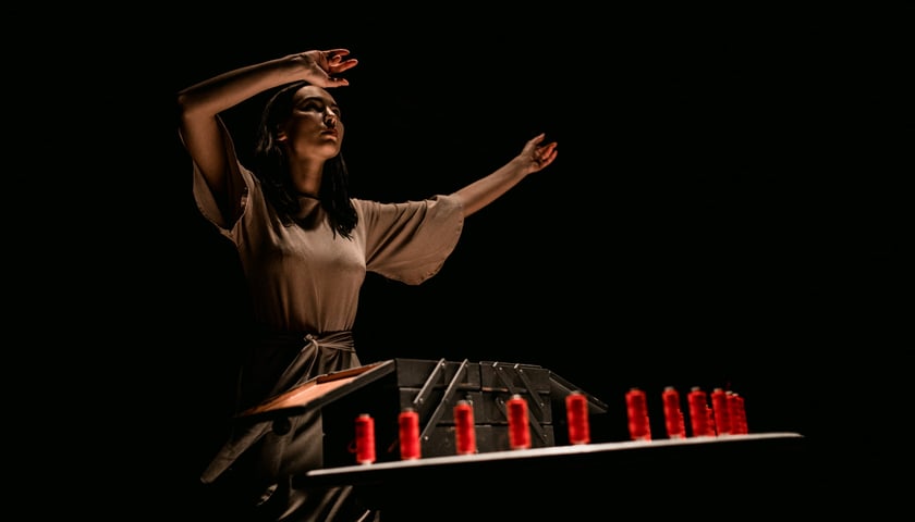 Młoda kobieta trzymająca w dłoniach czerwoną nić. Zdjęcie ilustracyjne pochodzące ze spektaklu Teatru na faktach - "Matki wyklęte". 