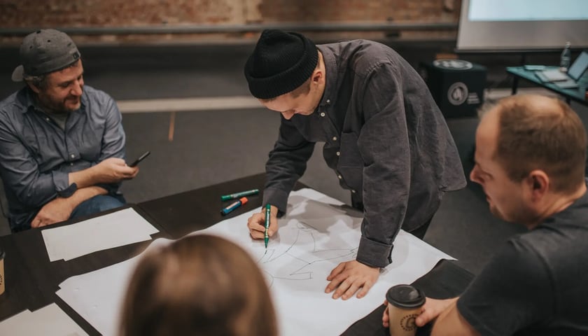 grupa mężczyzn pracujących nad wspólnym projektem przy stole, zdjęcie ilustracyjne