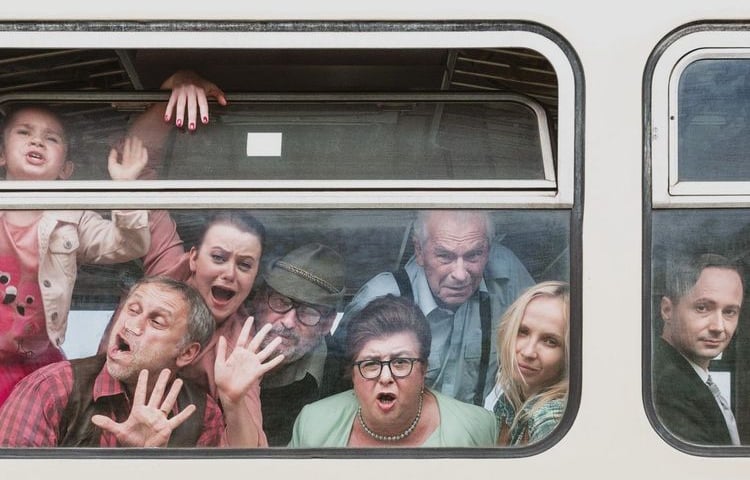 Ludzie za oknem przedziału w pociągu robiący dziwne miny