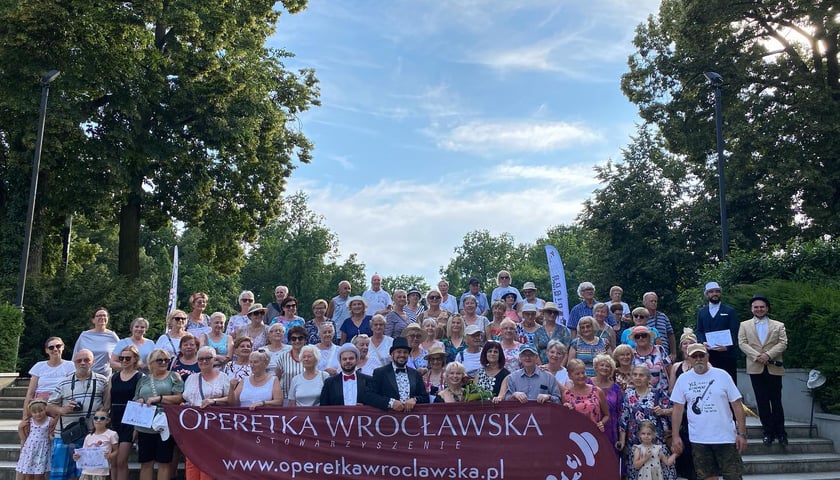 Artyści Operetki Wrocławskiej i publiczność pierwszych w tym roku koncertów na wynos trzymająca transparent Operetki Wrocławskiej