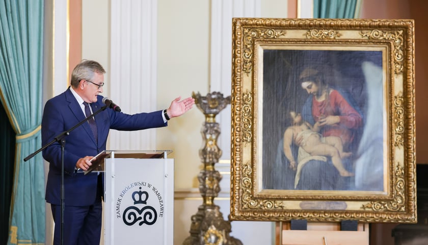 Piotr Gliński, minister kultury i dziedzictwa narodowego przy mównicy wskazuje dłonią na ustawiony obok na sztalugach obraz „Madonna z dzieciątkiem”