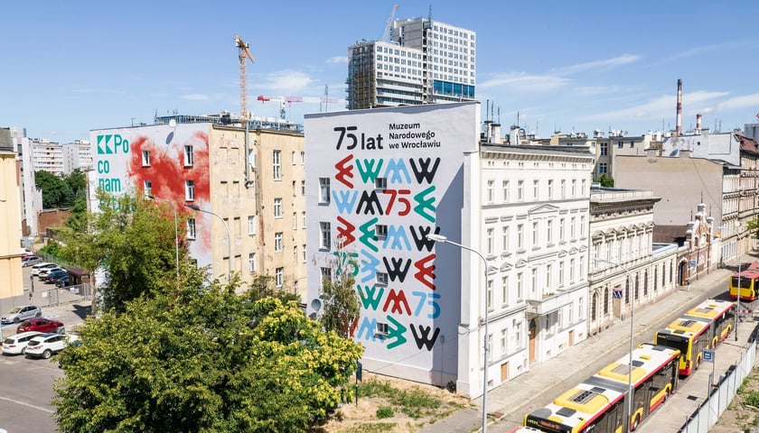 Widok na ścianę kamienicy z muralem z logotypami oraz nazwą Muzeum Narodowego we Wrocławiu