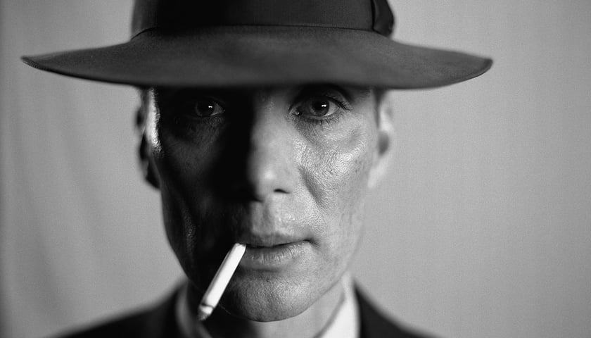 Kadr z filmu  „Oppenheimer”. Czarno-biały portret głównego bohatera. Na zdjęciu aktor Cillian Murphy w kapeluszu i z papierosem