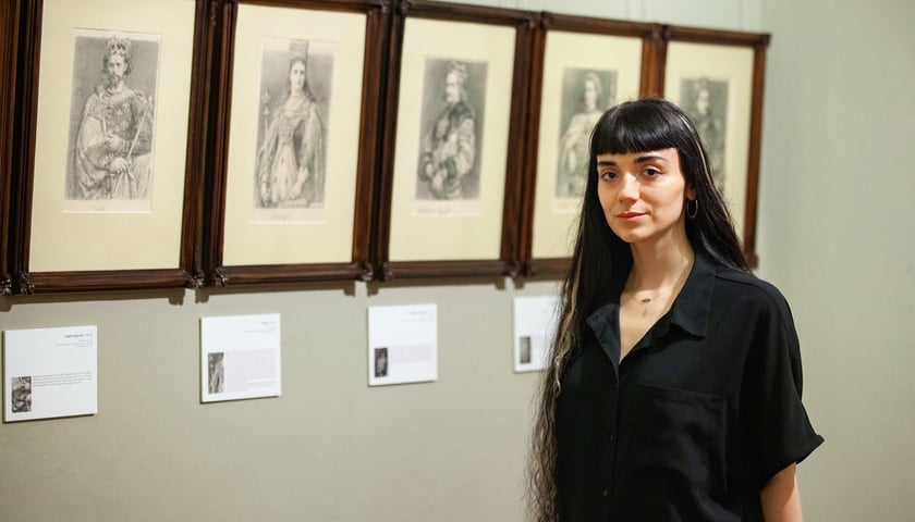 Natalia Sienkiewicz, kuratorka, na tle rysunków Jana Matejki z cyklu "Poczet królów polskich"