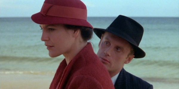 Kobieta w czerwieni i mężczyzna czerni obok siebie – kadr z filmu „Blaszany bębenek” z Danielem Olbrychskim