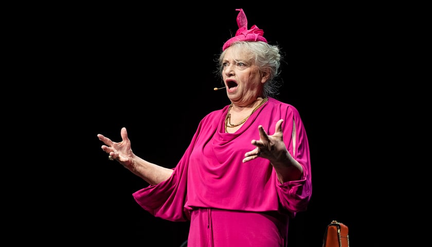 Anna Seniuk w różowej sukience i różowym stroiku na głowie w monodramie „Księga ziół i nie tylko”