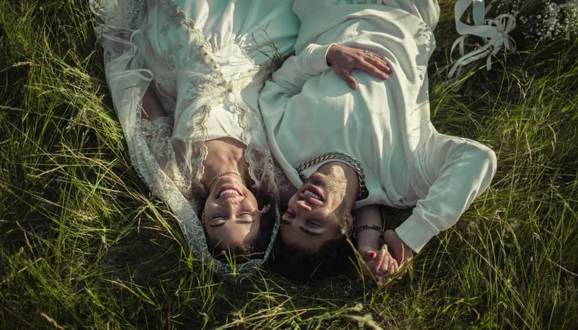 Powiększ obraz: Kadr z serialu "Infamia" Netflixa. Gita i Tagar w ślubnych strojach leżą na trawie