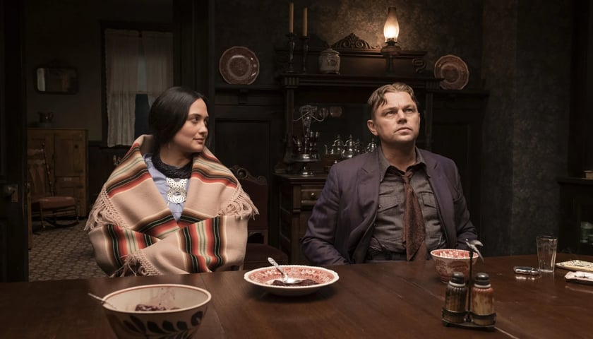 Kobieta i mężczyzna siedzą obok siebie przy stole, kadr z filmu „Czas krwawego księżyca”