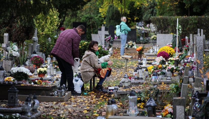 Kobieta siedząca na ławeczce przed grobem na cmentarzu