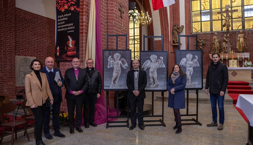 <p>Osoby zaangażowane w proces powrotu figurek anielskich do kościoła św. Marii Magdaleny na tle zdjęć aniołk&oacute;w</p>