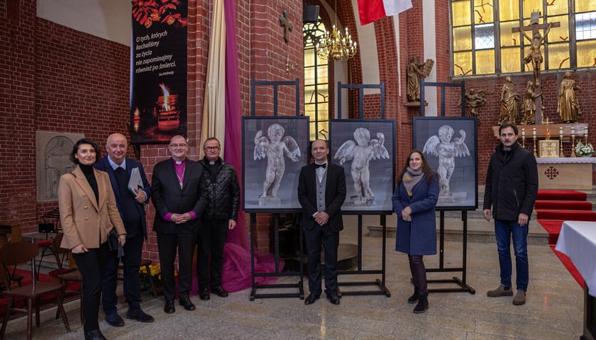 Powiększ obraz: <p>Osoby zaangażowane w proces powrotu figurek anielskich do kościoła św. Marii Magdaleny na tle zdjęć aniołk&oacute;w</p>