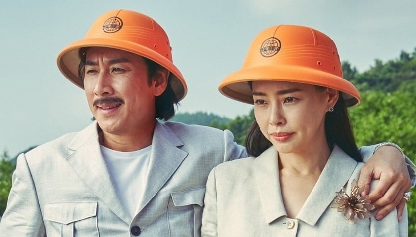 Mężczyzna i kobieta stoją obok siebie, na głowach mają takie same pomarańczowe kapelusze, kadr z filmu „Zabójczy romans”
