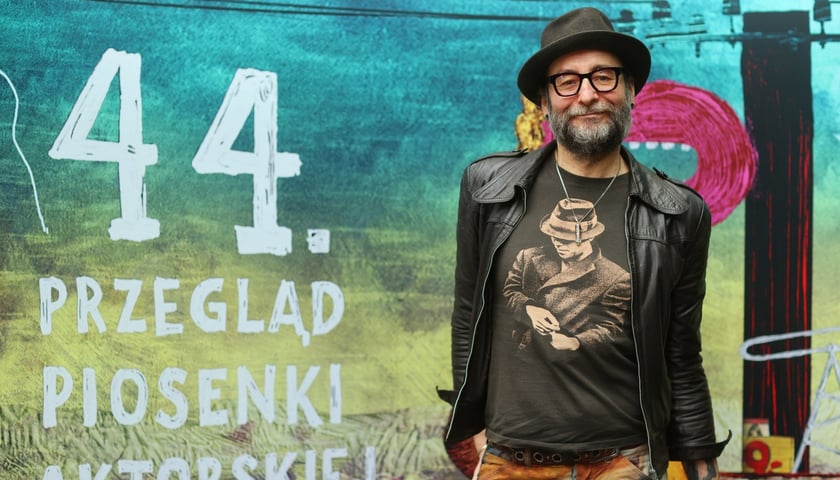 Cezary Studniak, dyrektor artystyczny PPA 2024 na tle plakatu festiwalowego