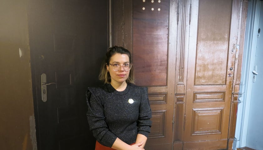 Powiększ obraz: Współkuratorka wystawy Anna Kurpiel na tle zdjęcia drzwi na Przedmieściu Oławskim