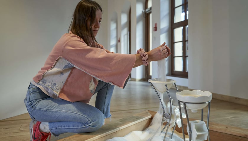 Kobieta sypiąca materię do leja, uruchamiając tym sposobem kołowrotek