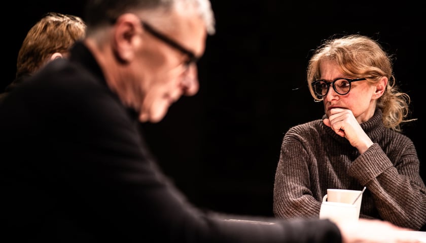Kobieta i mężczyzna siedzący przy stole. Kadr ze spektaklu "Koła", którego scenariusz powstał w ramach kursu prowadzonego w Instytucie Grotowskiego.