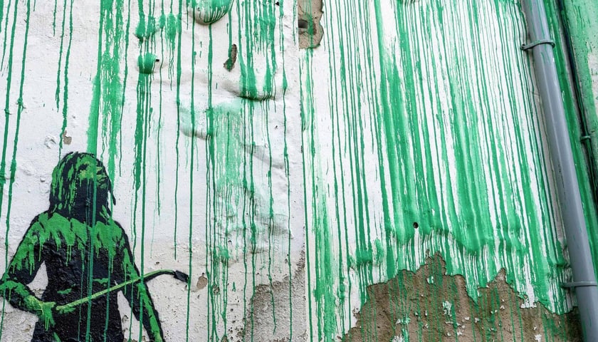 Mural w Finsbury Park (Islington) w Londynie: zielone strugi farby i zielono-czarna postać z urządzeniem rozpylającym farbę
