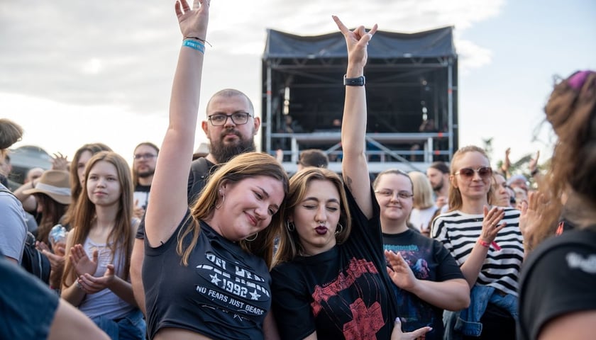 Kolaż dwóch zdjęć – na większym dziewczyna na koncercie trzymająca kartkę z napisem „Czy mogę kostkę do gitary?!?!”, na mniejszym tłum wrocławian na koncercie 3-Majówki