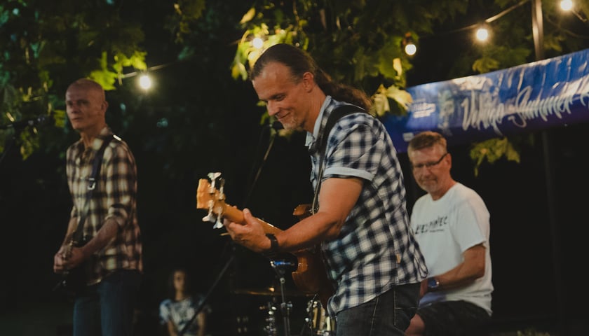 Trzech mężczyzn, dwóch gra na gitarze, jeden na perkusji. Koncert zespołu Outsider między przystankami Rondo a Sztabowa (24.08.2024) 