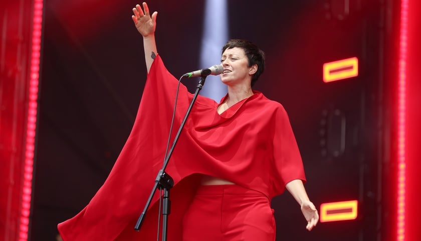 Natalia Przybysz przed mikrofonem i z uniesioną ręką, w czerwonym kostiumie (zdjęcie ilustracyjne)