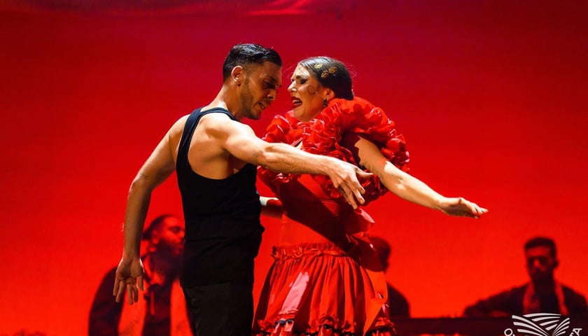 Kobieta w sukni czerwonej tańczy flamenco z mężczyzną ubranym w czarną koszulkę bez rękawów, spektakl Carmen w wykonaniu zespołu Barcelona Flamenco Ballet