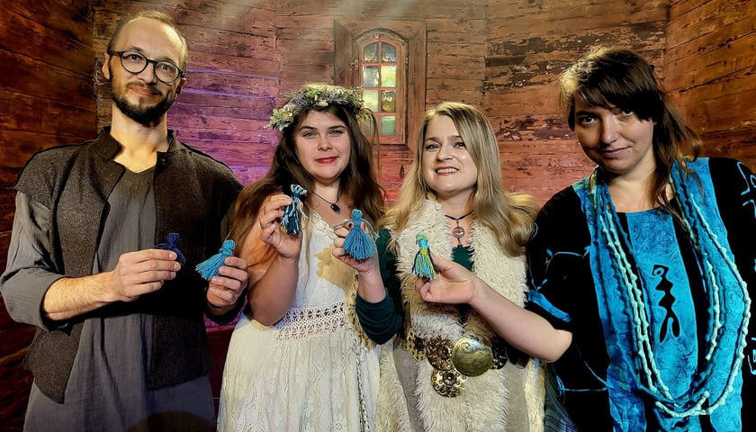 Czwórka artystów trzymających w rękach małe motanki - laleczki inspirowane słowiańskim folklorem