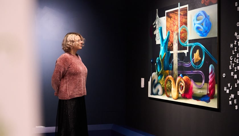 Młoda blondynka patrzy na obraz na wystawie „Nazwa bez wystawy, wystawa bez nazwy” w Krupa Art Foundation
