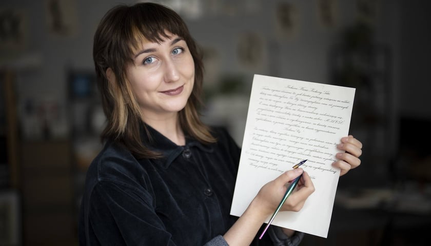 Uśmiechnięta Zuzanna Chróścik, trzymająca list i przyrząd do kaligrafii